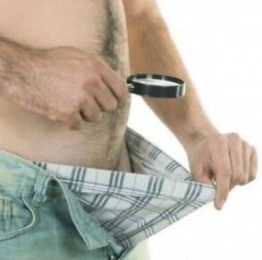 Ein Mann schaut unter seine Hose und möchte seinen Penis mit Gel vergrößern